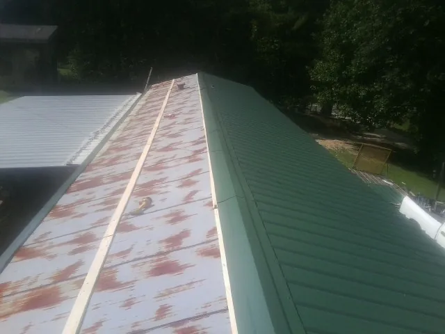 Old rusted panels beside newly installed green metal roofing — Wind Damage Roof Repair by Roofing Brothers in Oak Creek