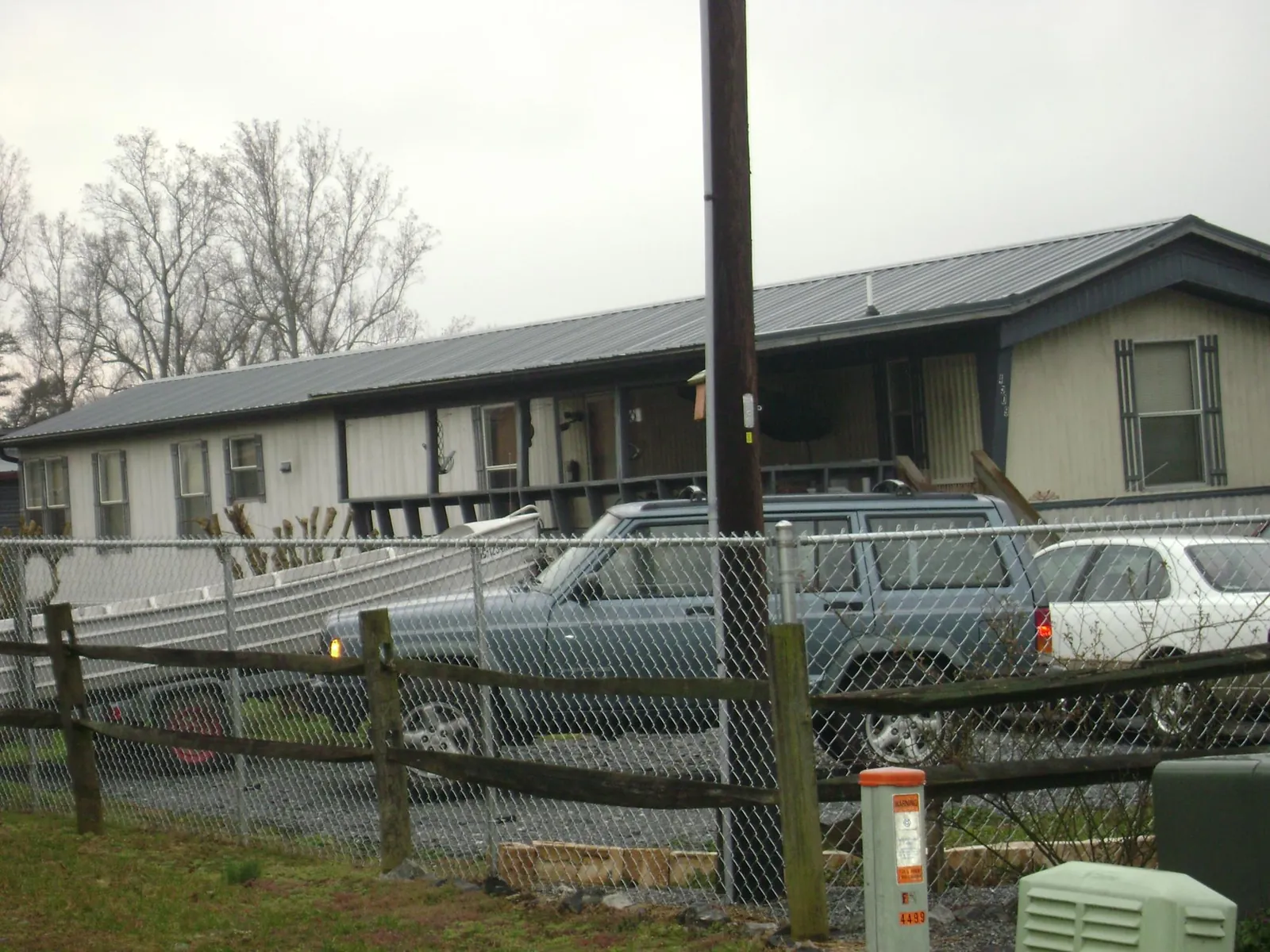Dark metal roof on a long single story building behind a chain link fence in Oak Creek