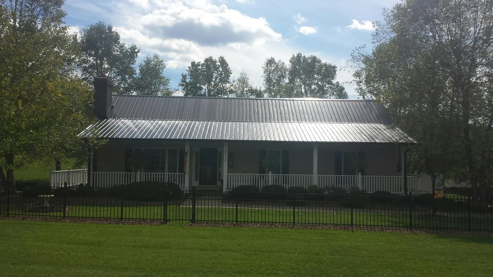 Gray metal roof on a brick ranch with a full width front porch — Gutter Guard Installation work by our crew in Oak Creek