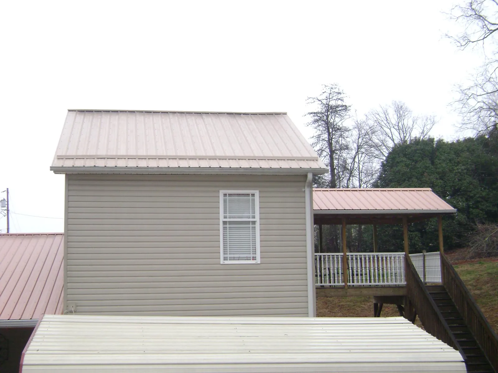 Tan metal roofs on a two story addition and attached porch, from a Roof Replacement job in Oak Creek
